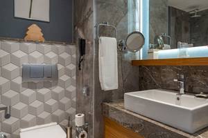 Ein elegantes Badezimmer im Baia Lara Hotel mit einer weißen Toilette, einem Waschbecken und einer Dusche.