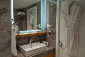 Badezimmer im Baia Lara Hotel mit Waschbecken, Spiegel und Handtüchern.