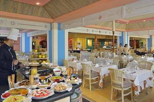 Frühstücksbuffet im Sol Palmeras Hotel mit einem Koch, der Gerichte zubereitet.