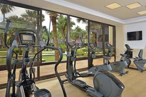 Fitnessstudio im Sol Palmeras Hotel mit Geräten und einem Mann, der etwas trägt.