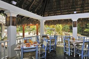 Terrasse des Sol Palmeras Hotels mit blauen Stühlen und Tischen, serviertem Frühstück und Blick auf Palmen und Strand.