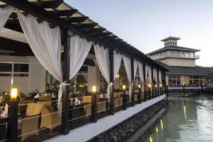 Terrasse des Sol Palmeras Hotels mit gepolsterten Stühlen und Tischen am Wasser.