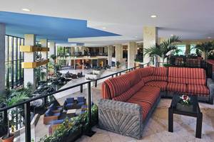 Lobby des Sol Palmeras Hotels mit roten Sofas, Tischen und Pflanzen.