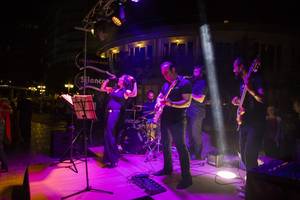Eine Band tritt auf einer Bühne im Hotel Liberty Lara auf, mit einer Sängerin, Gitarristen und anderen Musikern bei Nacht.