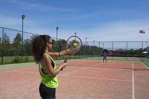 Eine Frau schlägt einen Tennisball auf einem Tennisplatz im Liberty Hotels Lara.