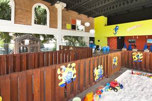 Innenansicht des Kinderbereichs im IFA Villas Bavaro Hotel mit Sandkasten, Spielzeug und bunten Wänden.