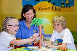 Eine Erzieherin und zwei Kinder spielen ein Spiel im Kinderclub des Grand Waterworld Makadi Hotels.