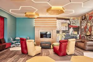 Lounge-Bereich im Atlantica Dreams Resort mit bunten Sitzsäcken, Tisch, Fernseher und Wandmalerei.