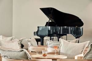 Loungebereich im Atlantica Dreams Resort mit schwarzem Klavier und Getränken auf dem Tisch.