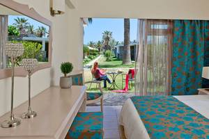 Innenansicht eines Zimmers im Civitel Creta Beach Hotel mit Blick auf eine Frau, die auf einer Terrasse sitzt.