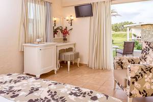 Hotelzimmer im Civitel Creta Beach mit offenem Fenster, Fernseher und Tisch mit Blumen.
