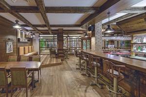 Innenansicht des Restaurants im VONRESORT Golden Coast mit Holzmöbeln, Ziegelwänden und einer Bar.