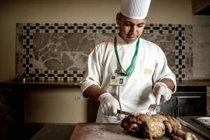 Koch im Grand Waterworld Makadi schneidet Fleisch mit Messer und Gabel