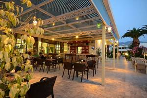 Abendliche Außenterrasse des Tropical Sol Hotels mit beleuchteten Tischen und Stühlen.