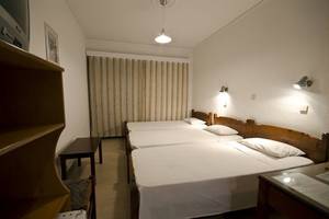 Drei Betten im Zimmer des Tropical Sol Hotels, alle mit weißen Laken bezogen.