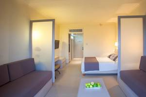 Innenansicht eines Hotelzimmers im Louis Imperial Beach mit Bett, Sofas und Tisch.