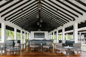 Loungebereich des Noku Maldives Hotels mit schwarzen und weißen Möbeln und Holzboden.