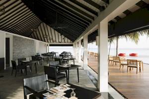 Innenbereich des Restaurants im Noku Maldives Hotel mit modernen Möbeln und Blick auf den Ozean.