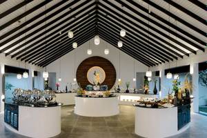 Innenansicht des Restaurants im Noku Maldives mit runden Tischen und hängenden Lampen.