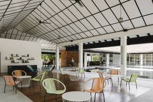 Loungebereich im Noku Maldives Hotel mit bunten Stühlen und Tischen auf einem Holzboden.