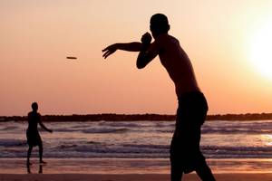 Silhouette von zwei Männern, die Frisbee am Strand spielen