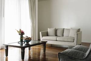 Wohnzimmer des Noku Maldives Hotels mit grauen Sofas, Tisch und Blumenvase.