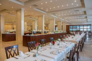 Innenansicht des Kresten Palace Restaurants mit langen, gedeckten Tischen und einer Theke im Hintergrund.