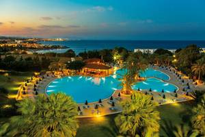 Luftaufnahme des Poolbereichs des Kresten Palace Hotels mit zwei Schwimmbecken und vielen Liegestühlen.