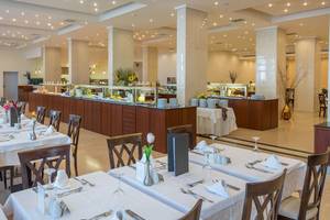 Restaurant im Kresten Palace Hotel mit langen Tischen, Stühlen und einer langen Buffettheke.