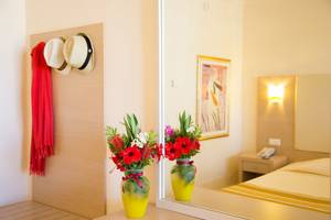 Ein Hotelzimmer mit zwei gelben Vasen voller Blumen, reflektiert in einem Spiegel, Kresten Palace Hotel.