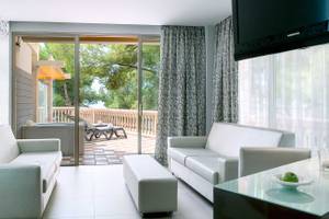 Wohnzimmer mit Balkon im Barcelo Illetas Albatros Hotel, mit modernem Interieur und Blick auf den Garten.