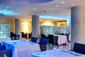 Innenansicht des Restaurants im Barcelo Illetas Albatros Hotel mit blauen Möbeln und weißen Tischen.