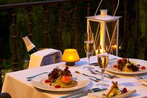 Ein Tisch mit Essen, Getränken und Kerzen auf einer Terrasse.
