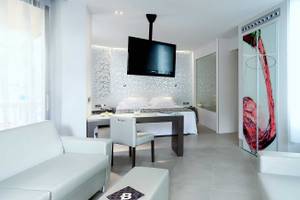 Innenraum des Barcelo Illetas Albatros Hotel mit weißem Bett, Schreibtisch und Fernseher.