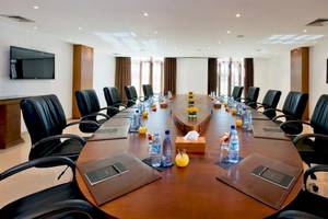 Ein Konferenzraum im Sofitel Agadir Royal Bay Resort mit einem großen Tisch, schwarzen Lederstühlen und Wasserflaschen.
