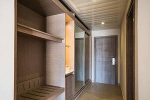 Eingangsbereich eines Hotelzimmers mit Garderobe, Waschbecken und Holzboden.