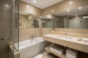 Ein modernes Badezimmer mit Badewanne, Waschbecken und Spiegeln im Steigenberger Alcazar Hotel.