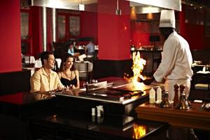 Ein Paar genießt das Essen im Restaurant des Iberostar Grand Rose Hall Hotels, während der Koch am Tisch Feuer macht.