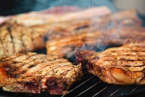 Gegrilltes Fleisch auf einem Grillrost mit Rauch und Feuer