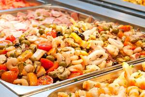 Ein Buffet mit Meeresfrüchten und Gemüse in Edelstahlschalen.