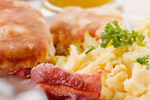 Frühstück mit Speck und Eiern, serviert auf einem weißen Teller.