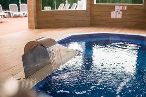 Ein Innenpool des Servatur Waikiki Hotels mit Wasserfall und blauem Wasser.