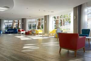 Innenansicht der Lobby des Servatur Waikiki Hotels mit bunten Stühlen und Tischen.