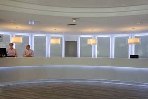 Empfangsbereich des Servatur Waikiki Hotels mit zwei Mitarbeitern hinter der Rezeption.