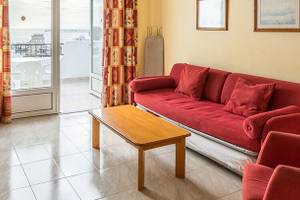 Wohnzimmer im Bluesea Callao Garden Hotel mit rotem Sofa, Couchtisch und Fernseher.