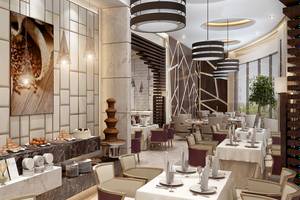 Innenansicht des Belad Bont Resorts Restaurant mit Marmorwänden, modernen Möbeln und mehreren Tischen mit Servietten und Geschirr.