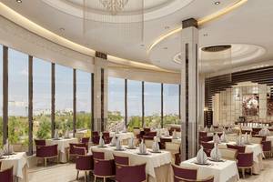 Restaurant im Belad Bont Resort mit Panoramafenstern und Ausblick auf die Stadt.