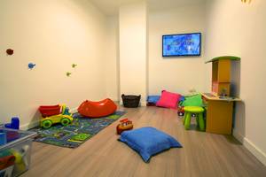Ein Kinderzimmer mit Spielzeug, einem Fernseher und verschiedenen Möbeln.