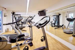 Fitnessraum im Hipotels Hipocampo Playa mit diversen Trainingsgeräten und einem großen Spiegel.