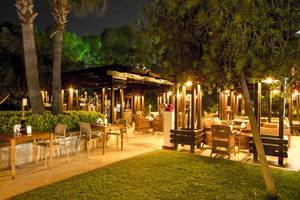 Außenbereich des Fame Residence Lara & Spa bei Nacht mit beleuchteten Tischen und Stühlen.